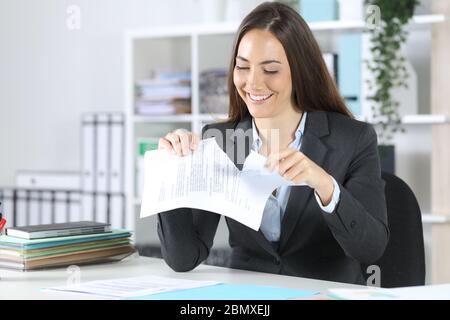 Buona donna esecutiva che rompe il documento del contratto seduto su una scrivania in ufficio Foto Stock