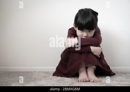 Solitaria triste bambina che tiene le ginocchia Foto Stock