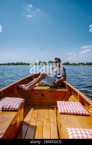 Giethoorn Netherlands uomini visitare il villaggio con una barca, vista del famoso villaggio con canali e case rustiche tetto di paglia in zona fattoria su un caldo Foto Stock
