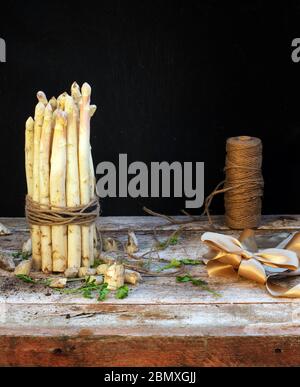 asparagi bianchi vista laterale su tavolo di legno con fondo nero Foto Stock