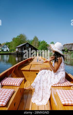 Giethoorn Olanda donna visitare il villaggio con una barca, vista del famoso villaggio con canali e case rustiche tetto di paglia in zona fattoria su un caldo Foto Stock