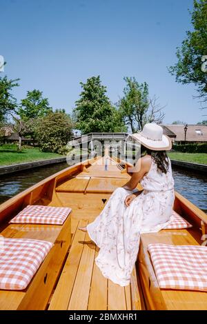 Giethoorn Olanda donna visitare il villaggio con una barca, vista del famoso villaggio con canali e case rustiche tetto di paglia in zona fattoria su un caldo Foto Stock