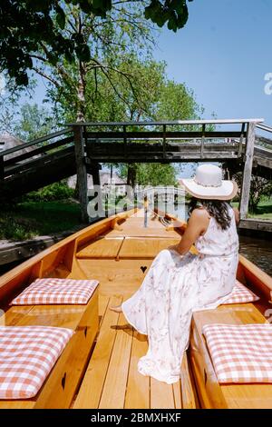 Giethoorn Olanda donna visitare il villaggio con una barca, vista del famoso villaggio con canali e case rustiche tetto di paglia in zona fattoria su un caldo Foto Stock