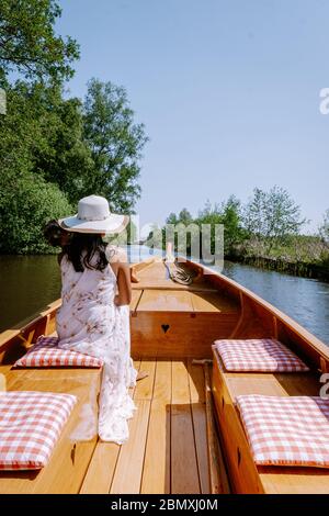 Giethoorn Olanda donna visitare il villaggio con una barca, vista del famoso villaggio con canali e case rustiche tetto di paglia in zona fattoria su un caldo Foto Stock