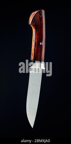Cacciatore coltello fatto a mano su sfondo nero. Maniglia - deserto ironwood. Spazio di copia. Foto Stock