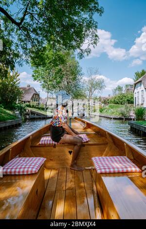 Giethoorn Olanda donna visitare il villaggio con una barca, vista del famoso villaggio con canali e case rustiche tetto di paglia in zona fattoria su un caldo Foto Stock