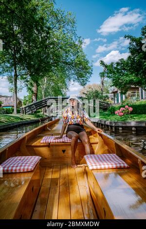 Giethoorn Olanda donna visitare il villaggio con una barca, vista del famoso villaggio con canali e case rustiche tetto di paglia in zona fattoria su un caldo Foto Stock