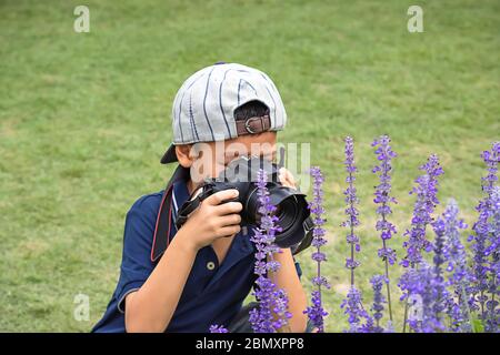 Ragazzo di mano tenendo la fotocamera per scattare foto nel parco. Foto Stock