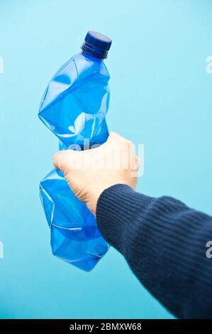 mano maschio che tiene un flacone di plastica blu Foto Stock