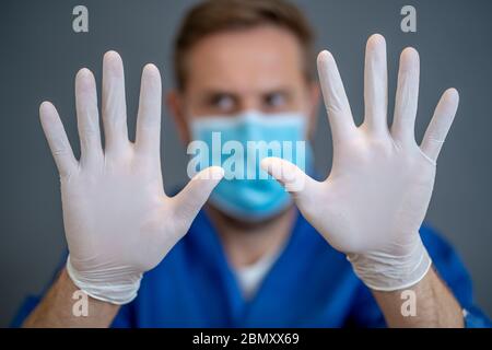 Focolaio COVID-19. Aiuto per fermare la diffusione del virus. Medico o infermiere che indossa maschera chirurgica facciale e guanti DPI che mostrano le mani in STOP gesture. Soggiorno s Foto Stock