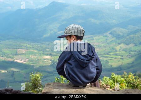 Ragazzi asiatici sedersi sulla roccia di vedere le montagne e il cielo di Phu Rua Parco Nazionale in Loei, Thailandia. Foto Stock