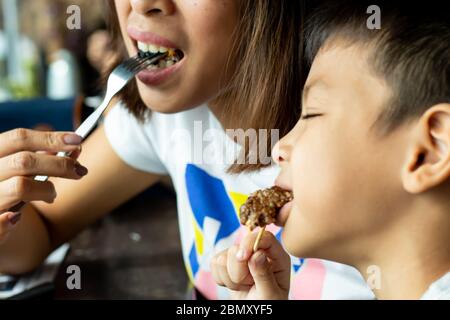 Madre e figlio mangiano hamburger neri. Foto Stock