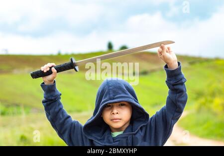 Ritratto di un ragazzo in possesso di una spada di legno giocare. Foto Stock