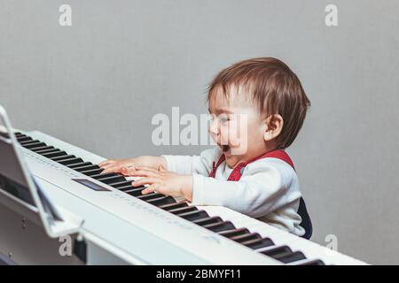 Piccolo bambino, bambino piccolo, divertirsi e suonare il pianoforte elettrico Foto Stock