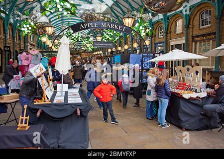 Persone che navigano merci in vendita presso Apple Market, Covent Garden, Londra Foto Stock