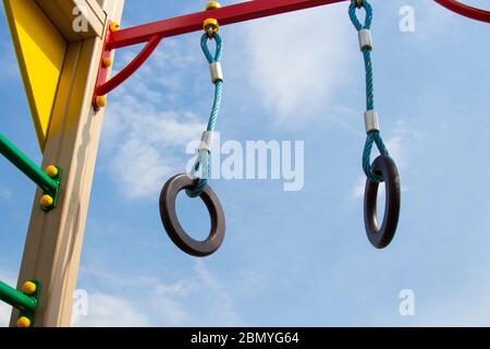 Gli anelli di ginnastica si appendono sul parco giochi del bar orizzontale. Contro il cielo blu. Foto Stock