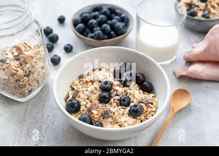 Colazione con cereali in ciotola servita con latte di mandorle e mirtilli. Mangiare pulito, dieta alimentare sana concetto Foto Stock