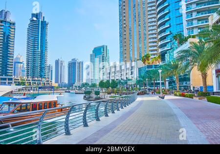 DUBAI, Emirati Arabi Uniti - 2 MARZO 2020: La passeggiata di Dubai Marina è fiancheggiata da cespugli topiari, palme lussureggianti e aiuole di fiori, che si estendono lungo l'alta ris Foto Stock