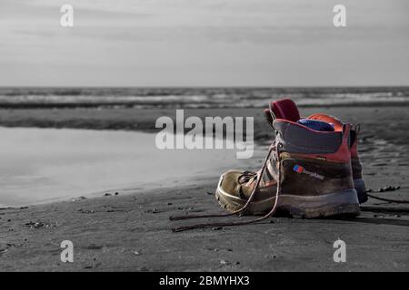 Primo piano di scarpe e calzini da passeggio per uomo isolati sulla sabbia di UK Beach. Foto Stock