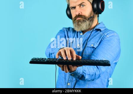 Cyber arena sportiva. Guida alla creazione di PC per il gaming. Impostazioni grafiche. Dipendenza da gioco. Cuffie e tastiera per giocatori hipster con cuscinetti da uomo. Giocare ai giochi per computer. Piattaforma di gioco online. Gioco moderno tempo libero. Foto Stock