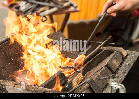 Puyallup, Washington, Stati Uniti. Fabbro femmina che riscalda un ferro nella fiamma di una fucina portatile. Foto Stock