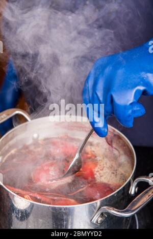 Donna che esamina le barbabietole per vedere se sono cucinate da loro poking con una forchetta. Questo è un passo nella preparazione di barbabietole in scatola sottaceto. Foto Stock