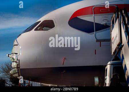 British Airways 787 Dreamliner con il cono del naso rimosso per la manutenzione e protetto da fogli di plastica attaccati da gaffa, dotto o nastro d'anatra. Foto Stock