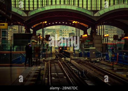 Un treno arriva alla Ferrovia leggera di Canary Wharf Docklands Stazione a Londra Est con vista di Tower Hamlets e. East India Dock Road sullo sfondo Foto Stock