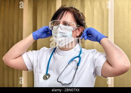 Un operatore sanitario utilizza dispositivi di protezione individuale, come occhiali, guanti e maschera chirurgica, durante la pandemia di coronavirus Foto Stock