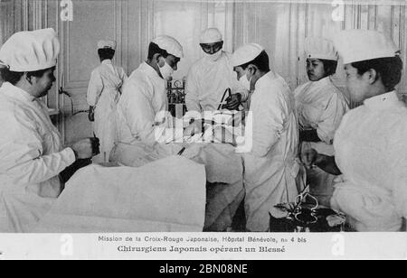 [ 1915 Giappone - Missione della Croce Rossa della prima Guerra Mondiale, Parigi ] – medici giapponesi operano su un soldato ferito in una missione della Società della Croce Rossa Giapponese presso l'ospedale temporaneo Hôpital Bénévole 4 bis, a Parigi, durante la prima Guerra Mondiale. L'ospedale si trova all'Astoria Hotel in rue de Presbourg. La Croce Rossa Giapponese la gestì dal 15 febbraio 1915 (Taisho 4) al 1 luglio 1916 (Taisho 5). Testo originale: "Mission de la Croix-Rouge Japonaise. Hôpital Bénévole, no 4 bis. Chirurgiens Japonais opérant un Blessé." cartolina vintage del xx secolo. Foto Stock