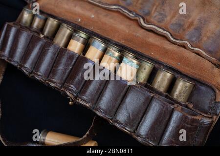 bandoliere da caccia in pelle marrone vintage con cartucce su sfondo nero Foto Stock