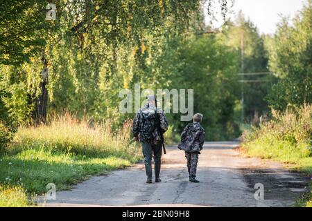 Padre e figlio insieme a caccia insieme. Camminando la strada in una foresta. Foto Stock