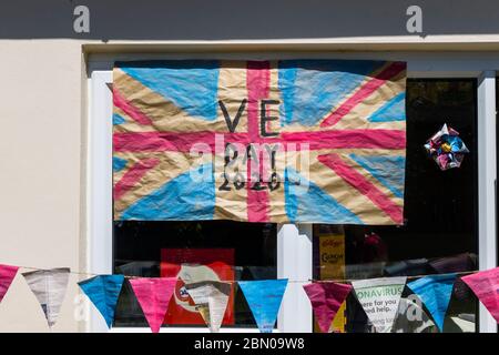 Colorato fatto in casa Union Jack bandiera e bunting per celebrare il VE Day, 8 maggio 2020, sulla parete e la finestra di una casa in Surrey, sud-est Inghilterra Foto Stock