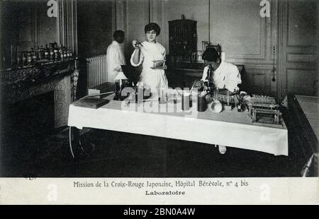 [ 1910s Giappone - Missione della Croce Rossa della prima Guerra Mondiale, Parigi ] – un medico giapponese controlla un esemplare al microscopio presso il laboratorio di una missione della Società della Croce Rossa Giapponese presso l'ospedale temporaneo Hôpital Bénévole 4 bis, a Parigi, durante la prima Guerra Mondiale. L'ospedale si trova all'Astoria Hotel in rue de Presbourg. La Croce Rossa Giapponese la gestì dal 15 febbraio 1915 (Taisho 4) al 1 luglio 1916 (Taisho 5). Testo originale: Mission de la Croix-Rouge Japonaise, Hôpital Bénévole, no 4 bis: Laboratoire cartolina d'epoca del XX secolo. Foto Stock