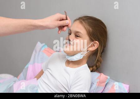 Una ragazza malata viene data medicina da un cucchiaio in bocca Foto Stock