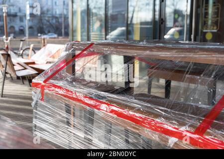 Il bar/ristorante all'aperto è chiuso per la quarantena durante l'epidemia di coronavirus. Sedie e tavoli sono legati con un nastro di avvertimento e coperti con poly Foto Stock