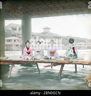 [ 1890 Giappone - Geisha e Maiko a Kyoto ] - diverse maiko e geisha si raffreddano su noryo yuka (piattaforme estive) istituito sotto un ponte sul fiume Kamogawa a Kyoto. foto di albume vintage del xix secolo. Foto Stock