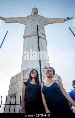 Due ragazze ispaniche che si trovano di fronte alla statua del Cristo del Rey a Cali Colombia Foto Stock