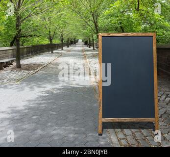 cartello bianco sul marciapiede su un percorso di ciottoli grigio alberato in un parco con spazio per la copia Foto Stock