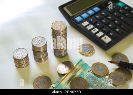 I mazzi di cinque monete di rupie sono in tre pile differenti. Sono presenti una calcolatrice e alcune banconote e dieci monete di rupie Foto Stock