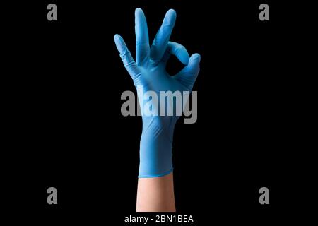 Mano del medico in guanti medici sterili in gesto di OK isolato su nero Foto Stock