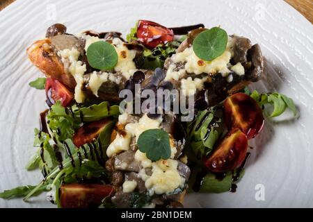 Crostini con funghi della foresta saltati, aglio, basilico e mozzarella. Tradizionale antipasto italiano su rucola, insalata di foglie di aragola. Foto Stock