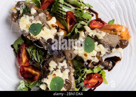 Crostini con funghi della foresta saltati, aglio, basilico e mozzarella. Tradizionale antipasto italiano su rucola, insalata di foglie di aragola. Foto Stock
