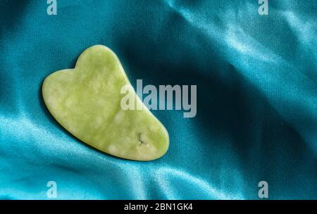 gua sha strumento in gemma naturale di verde giada. Spazio di copia Foto Stock