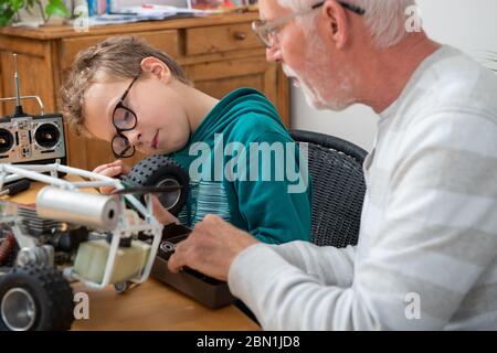 nonno e figlio ragazzino che riparano un modello di auto radiocomandata Foto Stock