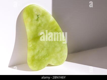 Gua sha strumento in gemma naturale di verde giada su sfondo bianco Foto Stock