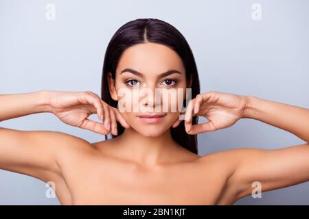 Concetto di bellezza e salute. Giovane bella signora mulatto latino sta toccando delicatamente la sua attraente pelle di bronzo sano, guardando dritto nella fotocamera. Così Foto Stock