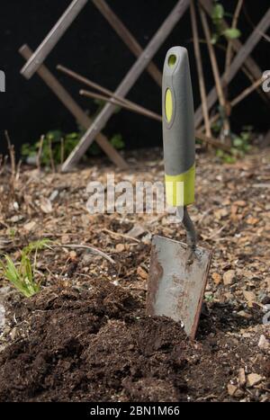 Primo piano di una cazzuola realistica bloccata in terra Foto Stock