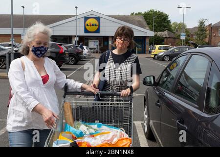 Il Venerdì maggio Bank Holiday nel Regno Unito e durante il blocco della pandemia di Coronavirus nel Regno Unito, due donne che indossano maschere fatte in casa emergono da una filiale del supermercato Lidl a Peckham, l'8 maggio 2020, a Londra, Inghilterra. Foto Stock