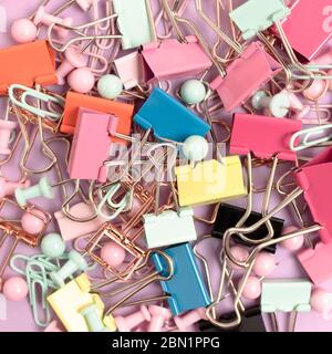 Trama composta da graffette e spille su sfondo rosa pastello. Foto Stock